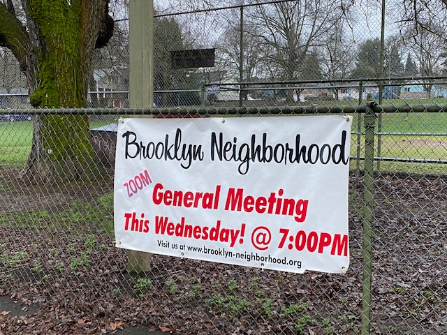 Banner hanging on fence at Brooklyn Park announcing general meeting: "Brooklyn Neighborhood, Zoom General Meeting this Wednesday! @ 7:00PM. Visit us at www.brooklyn-neighborhood.org."